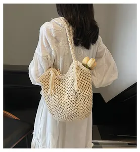 Detailed view of beige woven tote bag with fringe tassels and hand-knitted mesh texture