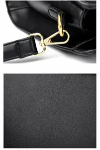Close-up of golden hardware clasp and pebble grain leather texture on black crossbody bag