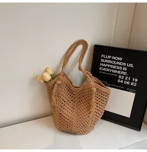 Detail of woven straw tote bag featuring hollow knit patterns and side tassel accents