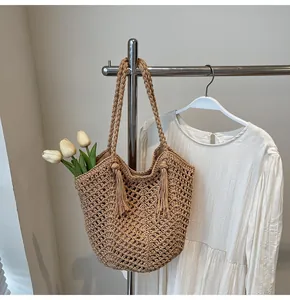 Detail of hand-woven straw tote bag with fringe accents and hollow crochet patterns