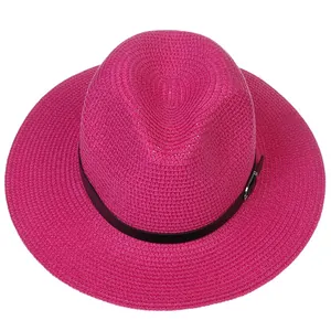 Détail d'un chapeau Panama rose fuchsia tissé avec ruban noir et boucle argentée