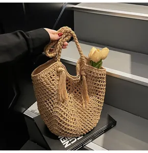 Close-up of hand-woven straw tote bag with intricate mesh pattern and fringe detail