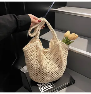 Close-up of beige woven tote bag with fringe detail and mesh texture on a book