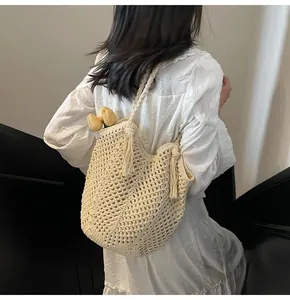 Detail of beige hand-woven crochet tote bag featuring fringe tassels and hollow knit pattern