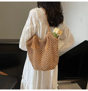Detailed close-up of handmade woven straw tote bag with elegant tassel and floral accents