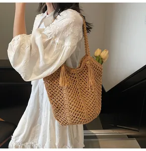 Detail of woven straw tote bag with tassel trim and floral accent in a lifestyle setting
