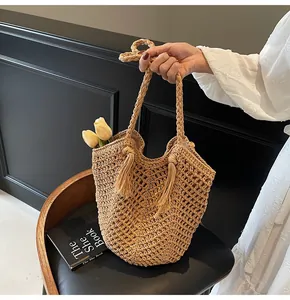 Detail of bohemian straw tote bag featuring intricate crochet patterns and stylish tassels