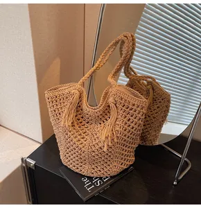 Close-up of woven straw tote bag featuring tassel detail and hollow-out knitting pattern