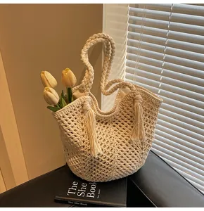 Detail of hand-crocheted cream tote bag with openwork weave and tassel accent