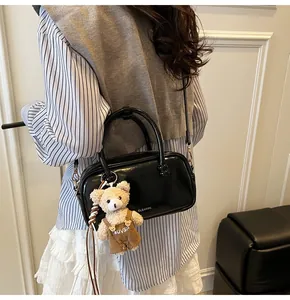 Glossy black Boston bag shown as a crossbody with a cute plush bear charm detail