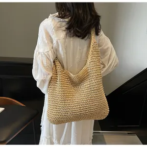 Detail of a large woven straw tote bag featuring intricate hollow knit texture and shoulder strap