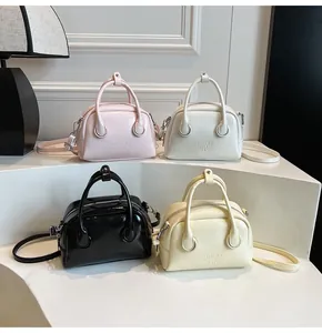 Mini bowling handbags in pink, white, black and beige shown on a white display stand