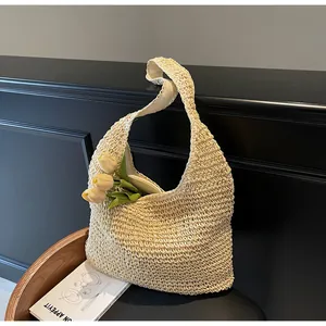 Detailed texture of hand-woven straw tote bag with wide strap and floral accent