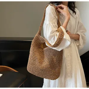 Detail view of woven straw tote bag texture and brown fabric lining on a shoulder strap