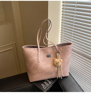 Detail of dusty pink tote bag with matte texture and cute brown teddy bear charm