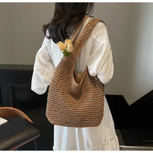Detail of a large brown woven straw tote bag featuring natural texture and tulip decorations