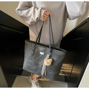 Detail view of grey marble texture tote bag featuring silver nameplate and plush bear charm