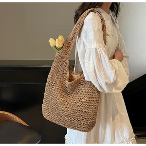 Detail of hand-woven straw tote bag with wide shoulder straps on white lace dress