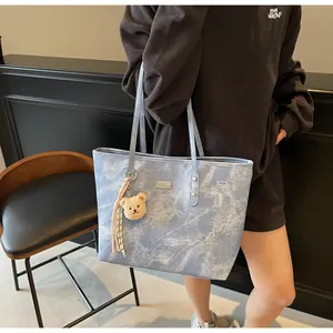 Detail of blue marble tote bag featuring double straps and cute bear doll charm