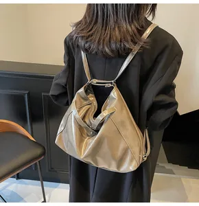 Détail d'un grand sac à dos hobo taupe brillant avec une finition métallique et de fines sangles