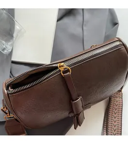 Detailed close-up of smooth metal zipper and textured leather tassel on retro brown bag