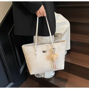 Detail of beige large tote bag with textured faux leather and plush bear charm decoration