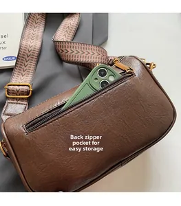 Detail of the back zipper pocket on brown leather crossbody bag for secure phone storage