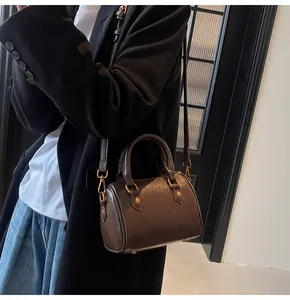 Detailed shot of dark brown mini Boston bag with glossy finish and gold metal hardware