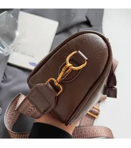 Detail of high-quality gold hardware and vintage textured strap on a brown leather bag