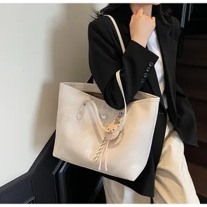Detailed macro view of large commute tote bag with a cute plush bear charm accessory