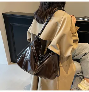 Vue détaillée du sac en cuir marron foncé avec surpiqûres blanches et design plié