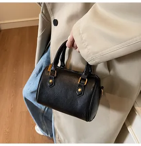 Detail of vintage black Boston bag with textured leather and gold-tone hardware on model