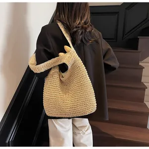 Detail view of the hand-woven texture and wide strap on this beige straw tote bag