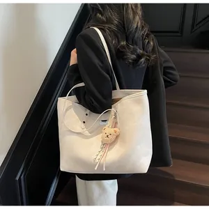 Close-up of off-white tote bag with brown bear charm on model's shoulder in vintage setting
