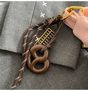 Detail of pretzel pendant and mini golden abacus keychain on a textured fabric