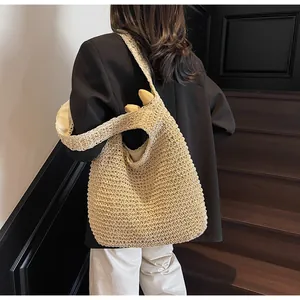 Close-up of lightweight woven straw hobo bag being worn by a model in black blazer
