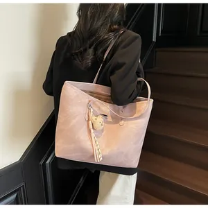 Detail of pink leather tote bag featuring a plush bear charm and stylish side tassels