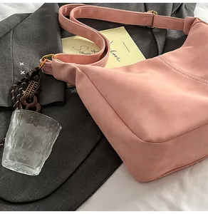 Detail of pink suede crossbody bag featuring fine stitching and gold metal hardware