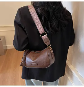 Detail of a brown leather shoulder bag with an adjustable wide jacquard patterned strap