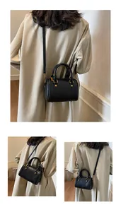 Detailed view of black Boston bag with pebbled leather texture and golden metal hardware
