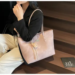 Close-up of casual tote bag with bear charm and tassel detail in a street style setting