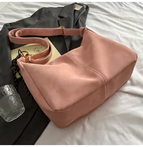 Detail of dusty pink faux suede tote bag with decorative stitching and gold hardware