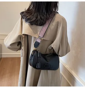 Close-up of black crossbody bag with textured wide shoulder strap and gold hardware