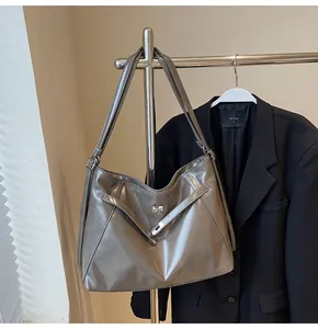 Détail d'un grand sac fourre-tout métallisé avec fermoir rotatif argenté et cuir brillant