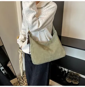 Detail of sage green suede hobo bag showing vertical stitching and soft matte texture