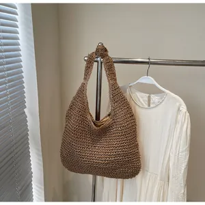 Detail of hand-woven straw tote bag featuring decorative knot strap and hollow texture