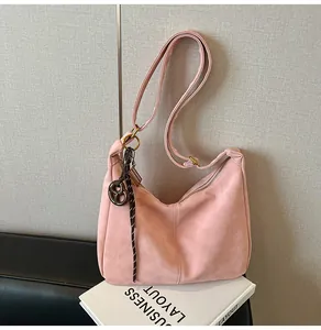 Detail of pink matte hobo bag with adjustable strap and vintage pretzel charm accessory