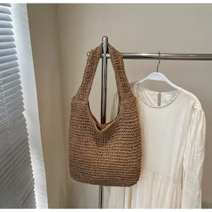 Close-up of the woven texture and wide shoulder strap on this brown straw tote bag