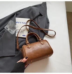 Detail of a brown vintage cylindrical Boston bag with gold rivets and leather texture