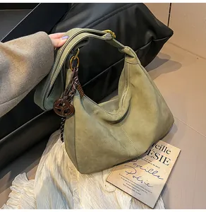 Detail of olive green suede hobo bag with vintage metal buckle and braided brown pendant